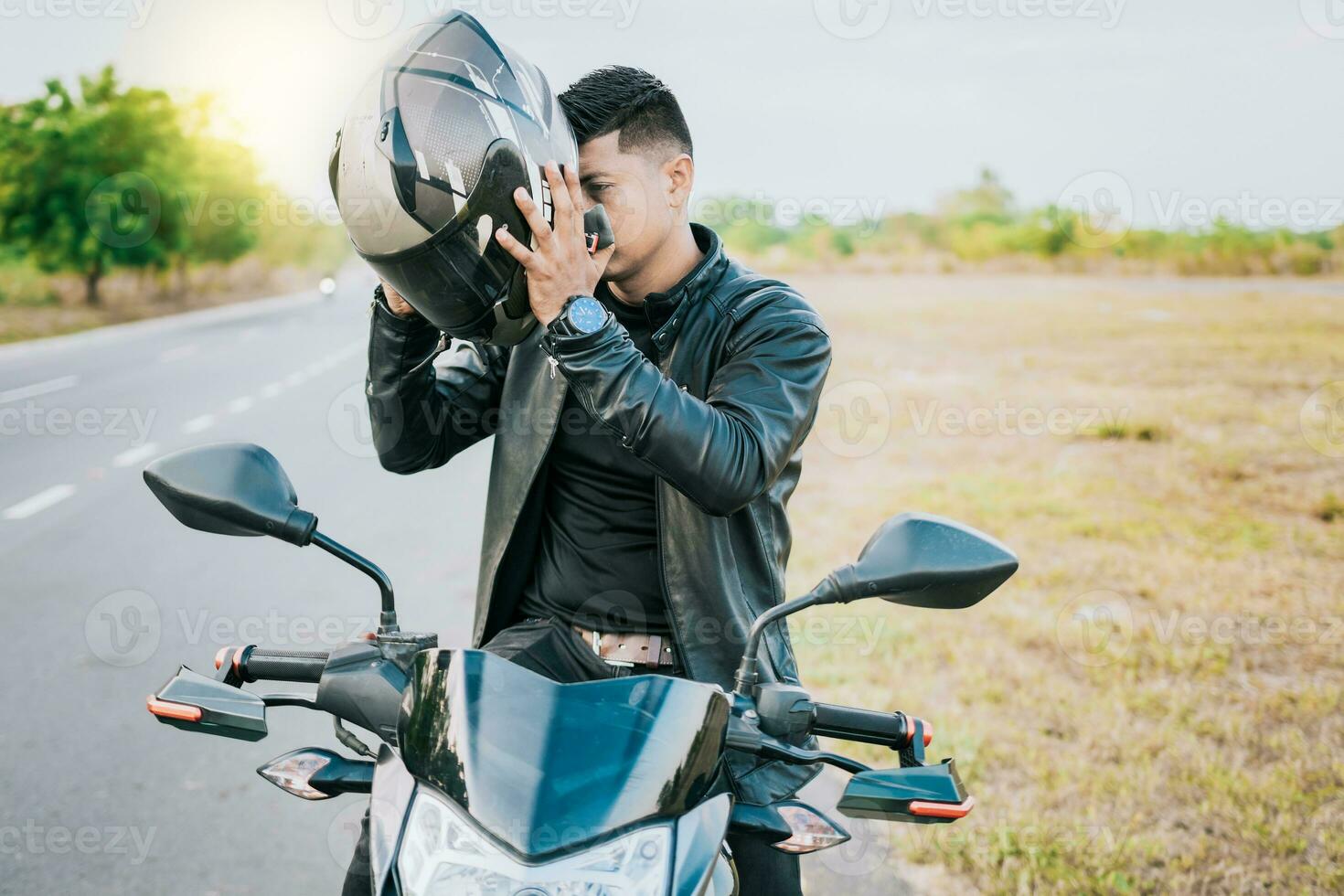 männlich Biker auf Motorrad Putten auf Sicherheit Helm. Biker Motorrad Sicherheit Konzept, jung Motorradfahrer Mann Putten auf Sicherheit Helm draußen foto