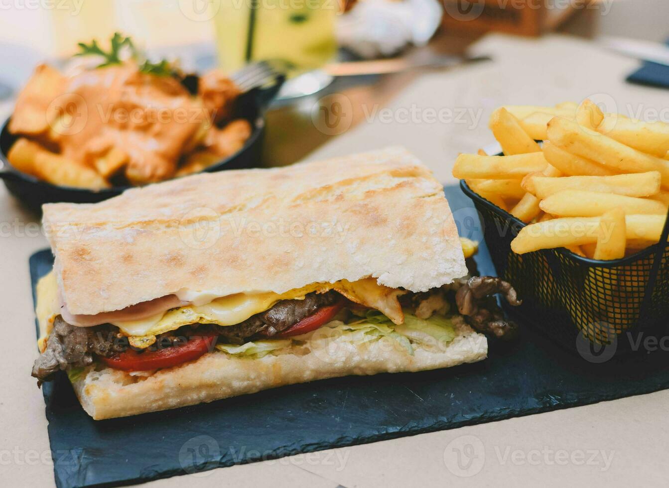 köstlich Rindfleisch Filet Sandwich mit Schinken und Käse, begleitet durch Französisch Fritten foto