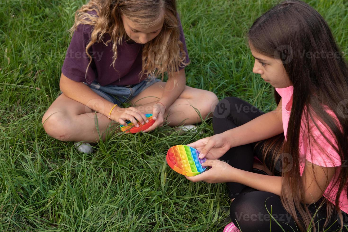 Mädchen spielen im Freien mit buntem Silikon-Touch beliebtes Pop-It-Spielzeug foto