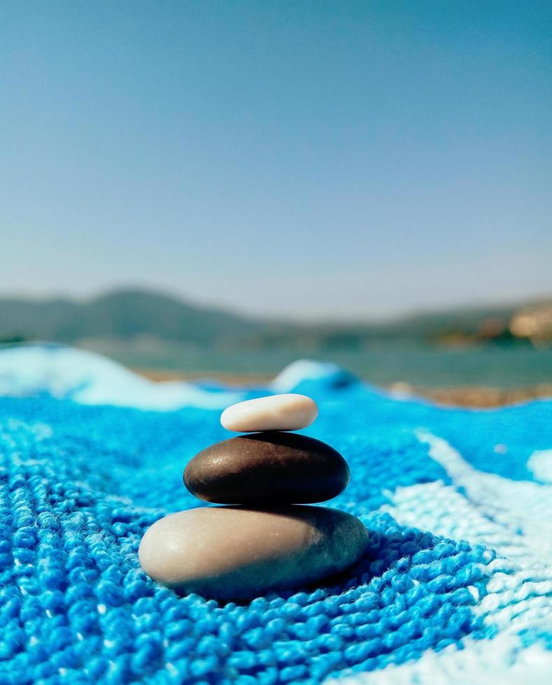 Stapel Kieselsteine am Strand auf blauem Handtuch foto