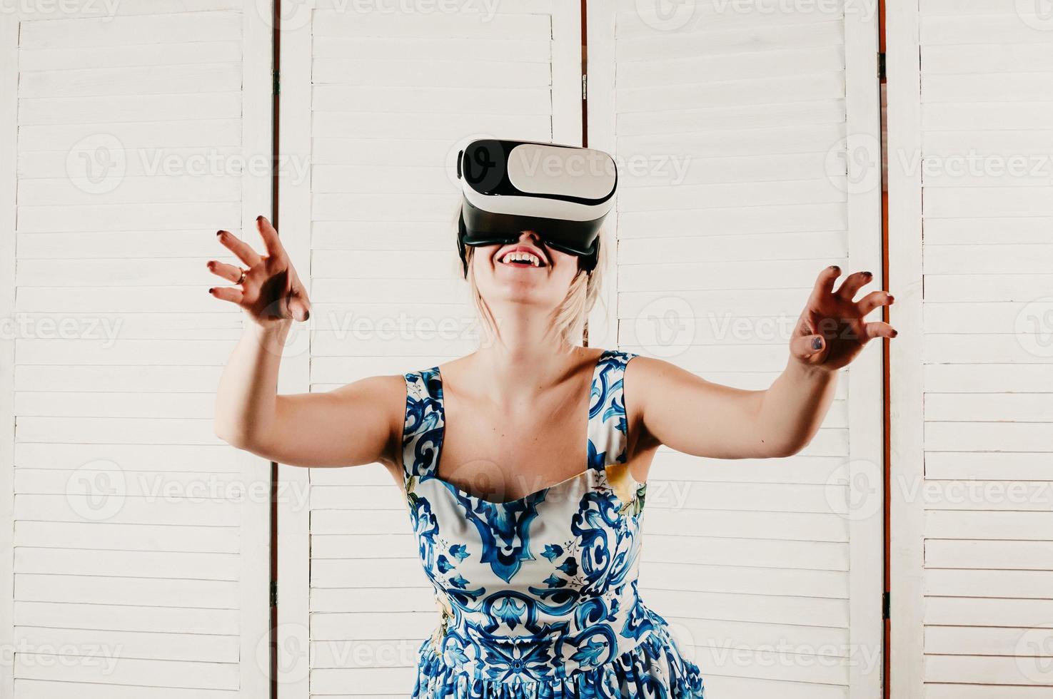 blonde Frau mit VR-Brille, die ihre Hände in die Luft zeigt foto