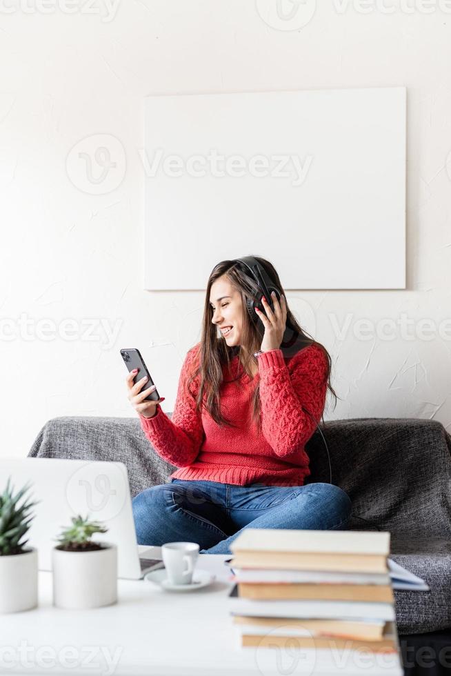 Frau im roten Pullover sitzt auf der Couch und telefoniert foto