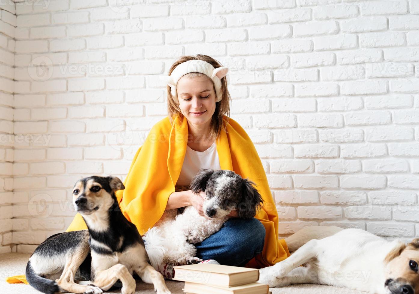 lustige junge frau in gelb kariert, die mit ihren hunden sitzt und ein buch liest foto