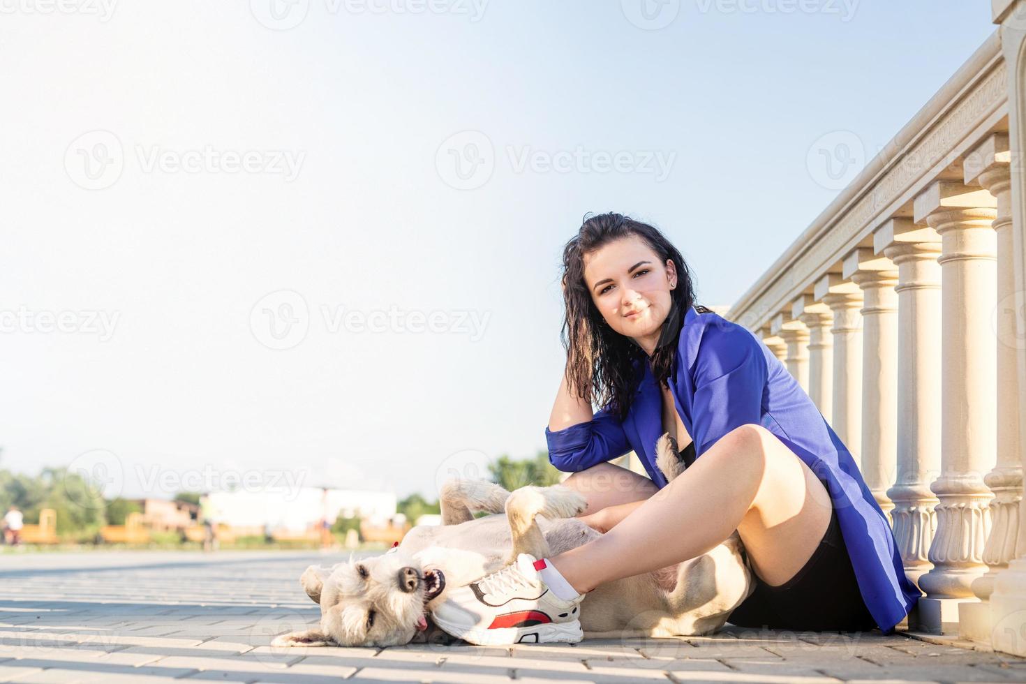 junge fröhliche Frau, die mit ihrem Hund im Park spielt foto