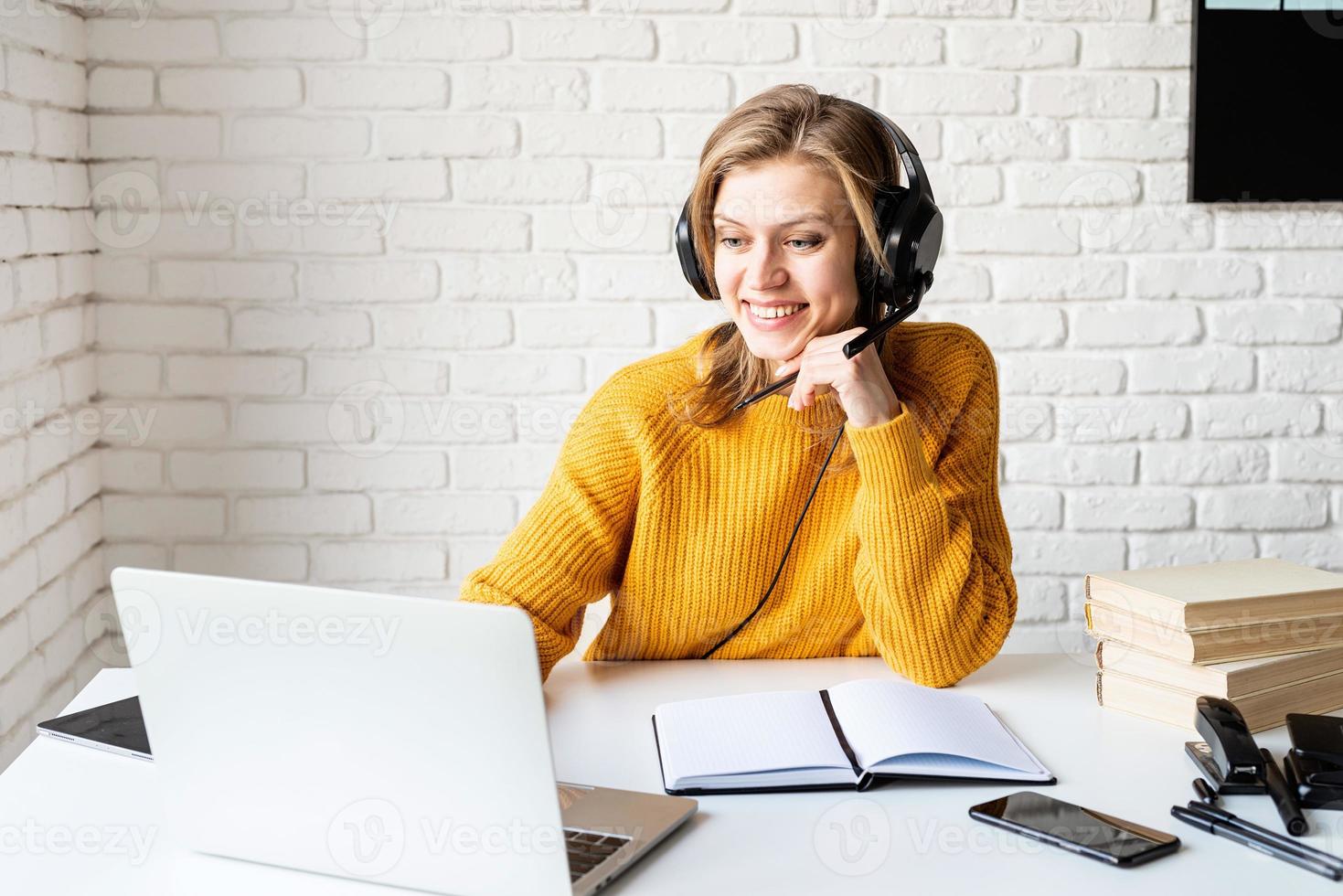 junge Frau in schwarzen Kopfhörern, die online mit Laptop studiert? foto