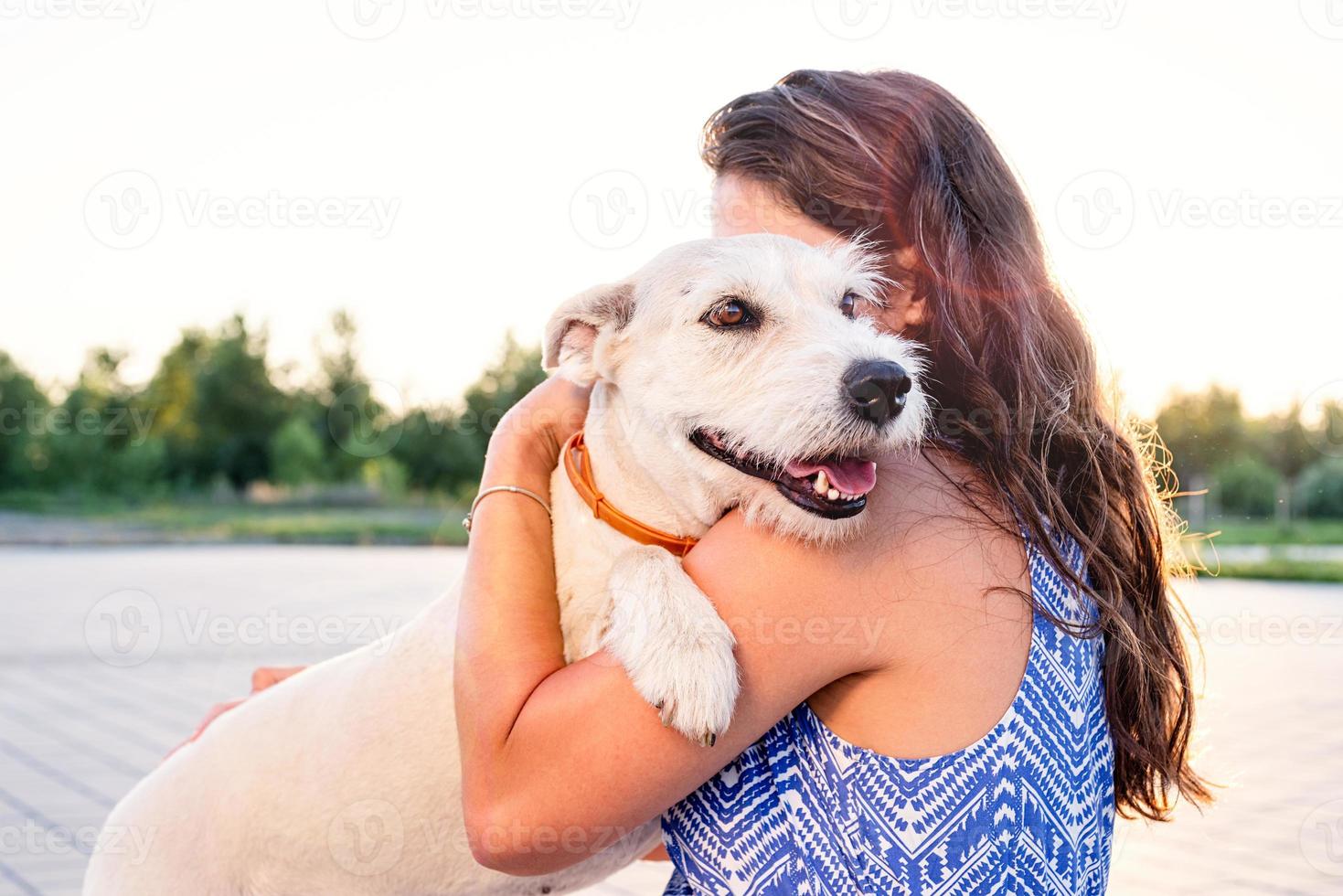 junge attraktive Frau, die ihren Hund im Park umarmt foto