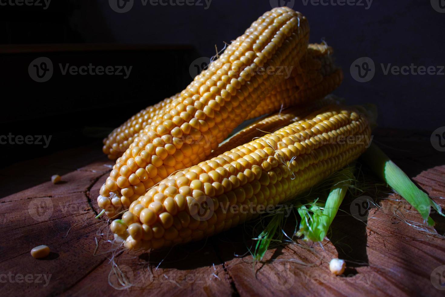 Maiskolben mit Blättern auf Holzhintergrund. frisches pflanzliches Essen foto