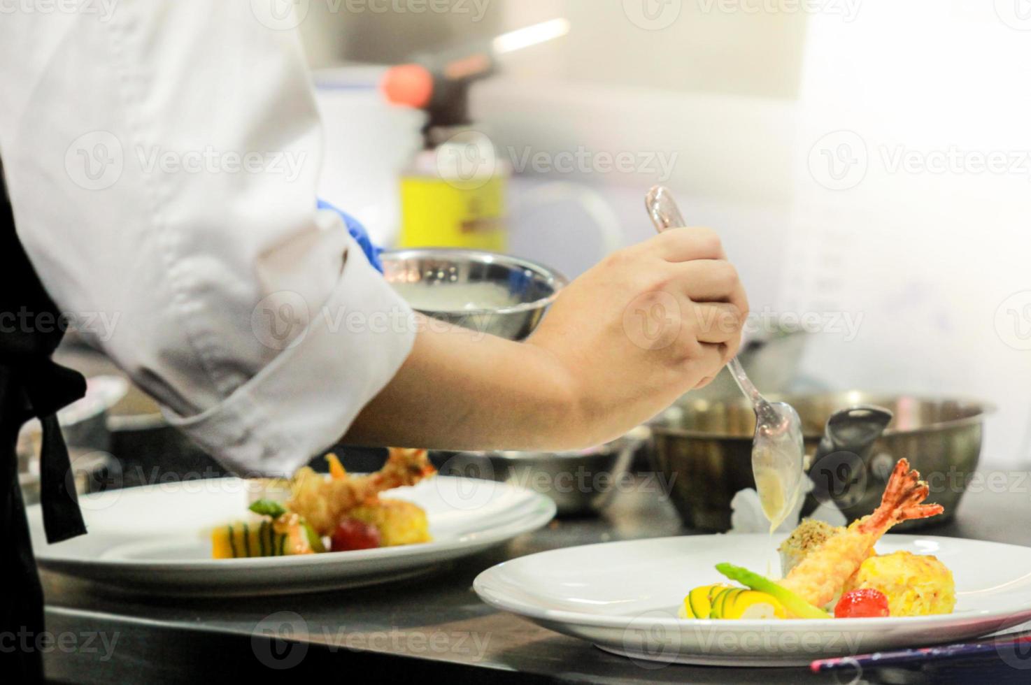 Koch bereitet Essen in der Küche zu, Koch kocht, Koch dekoriert Gericht foto