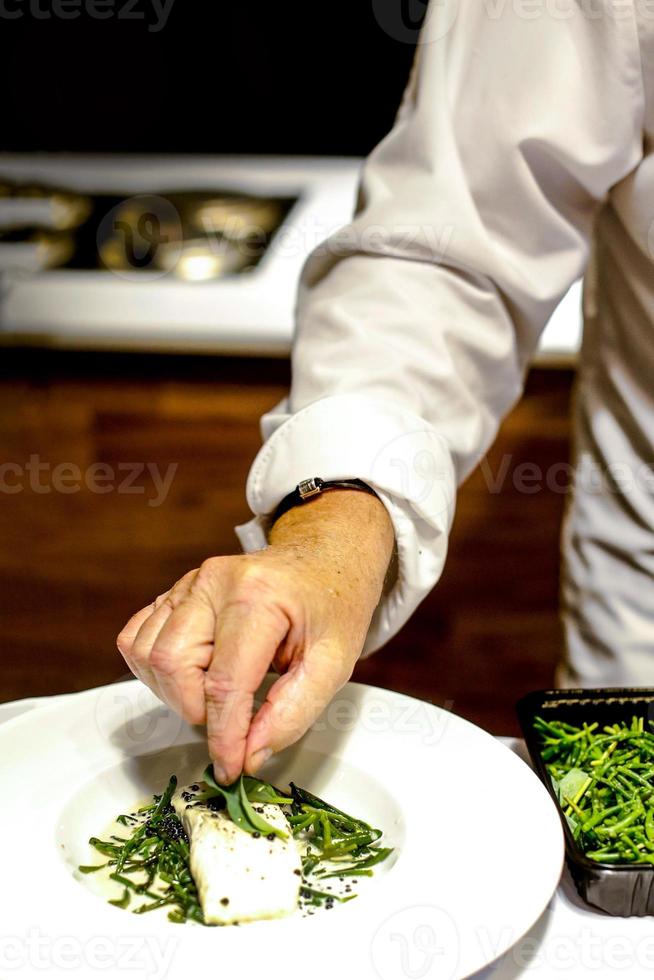 Koch kocht, Koch bereitet Essen zu, Koch dekoriert Gericht in der Küche foto