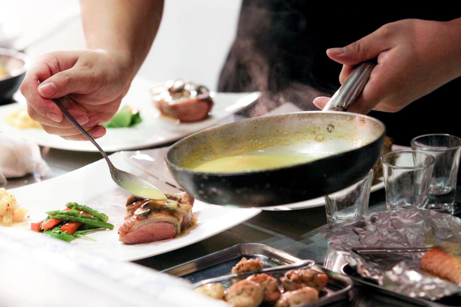 Koch kocht, Koch bereitet Essen zu, Koch dekoriert Gericht in der Küche foto