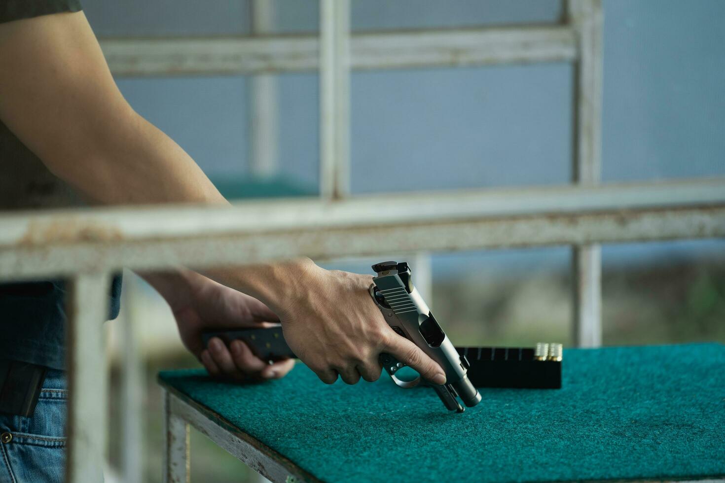 Shooter-Mann, der in ein Waffenmagazin geladen wird, und schwarze Kleidung bereiten sich auf das Schießen mit Kurzwaffen auf dem Schießstand vor. Schießsport zur Meditation und Selbstverteidigung, Freizeitaktivitäten. foto