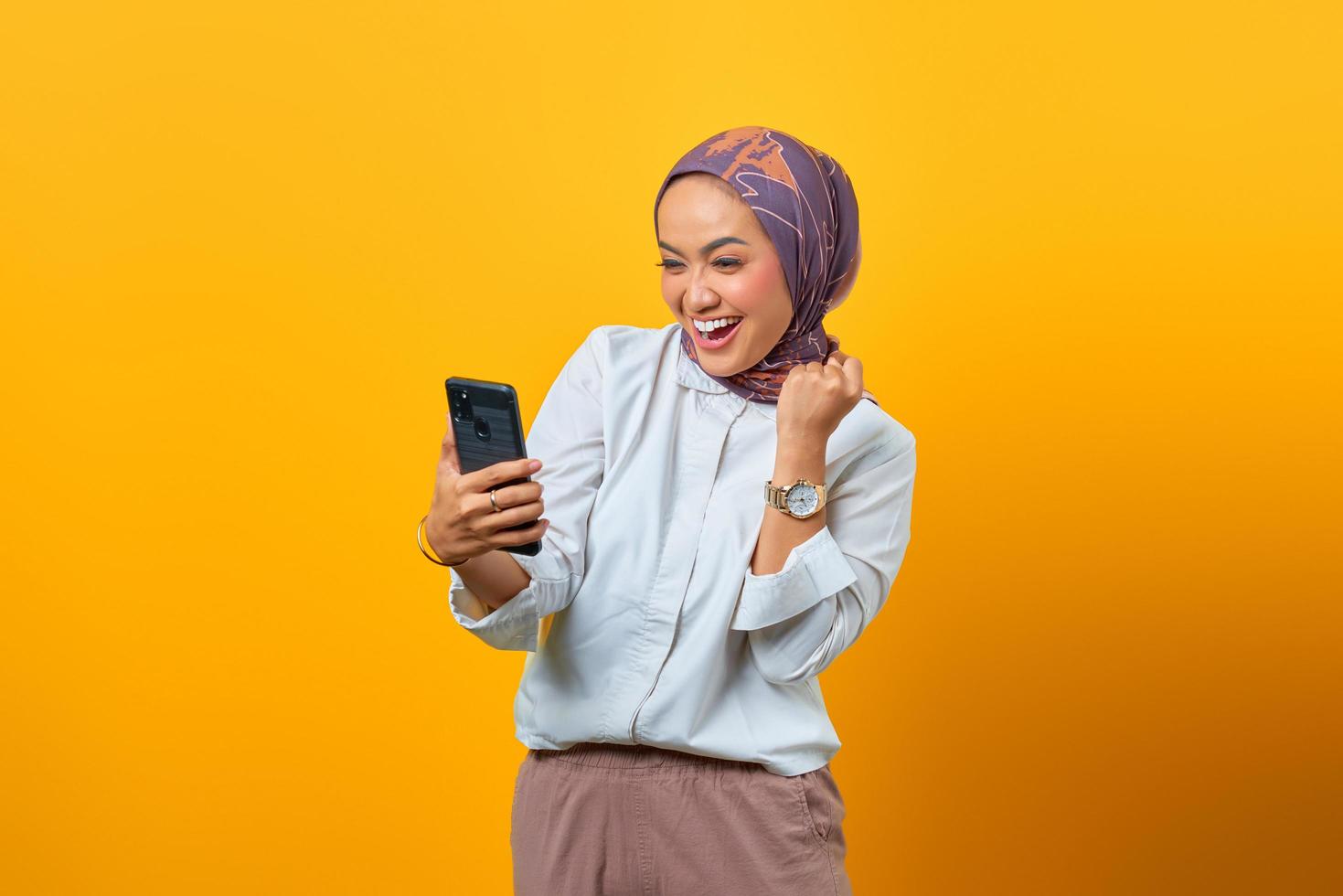 Aufgeregte asiatische Frau, die auf Smartphone schaut und gute Nachrichten erhält foto