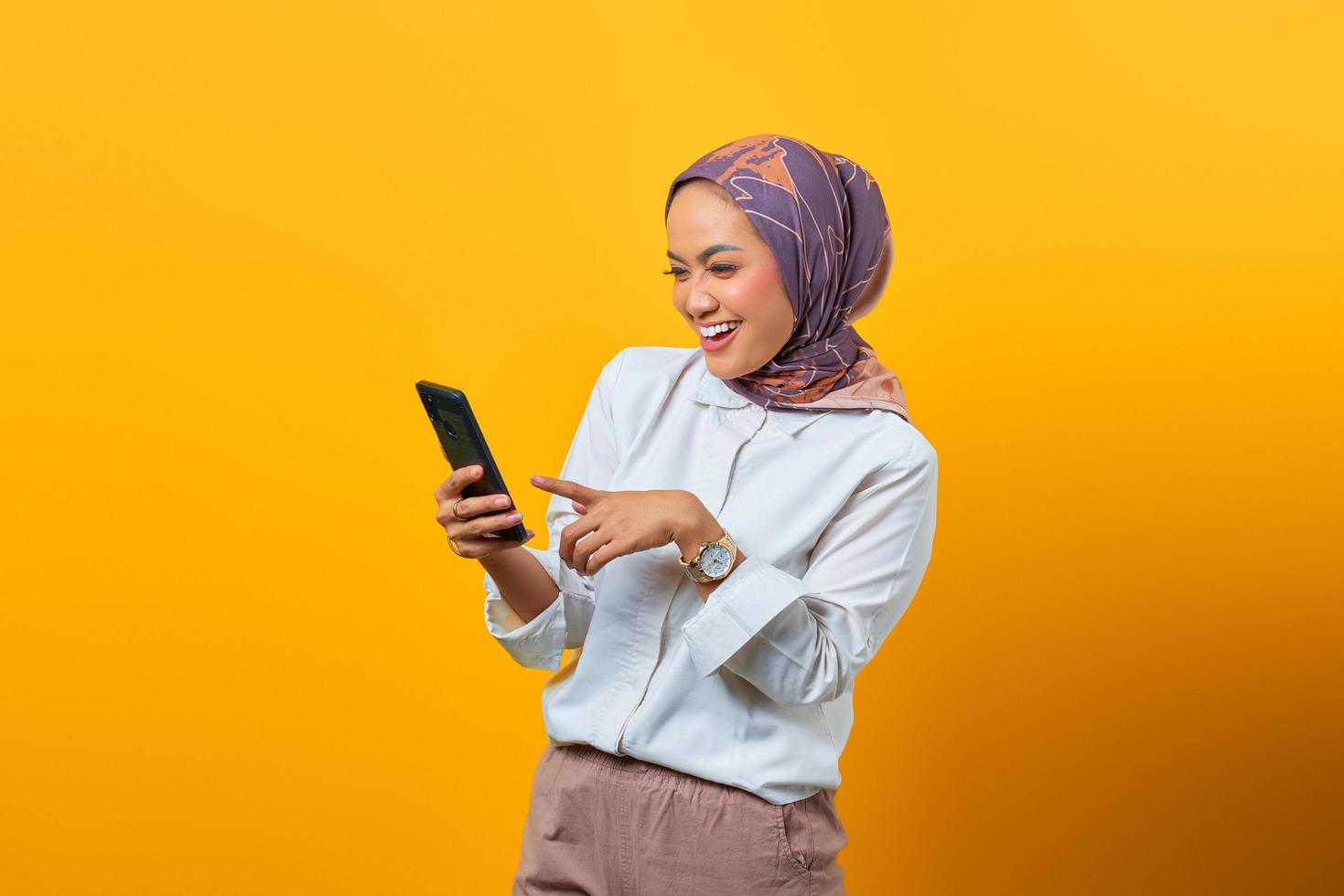 Fröhliche asiatische Frau, die auf das Smartphone schaut und gute Nachrichten bekommt foto