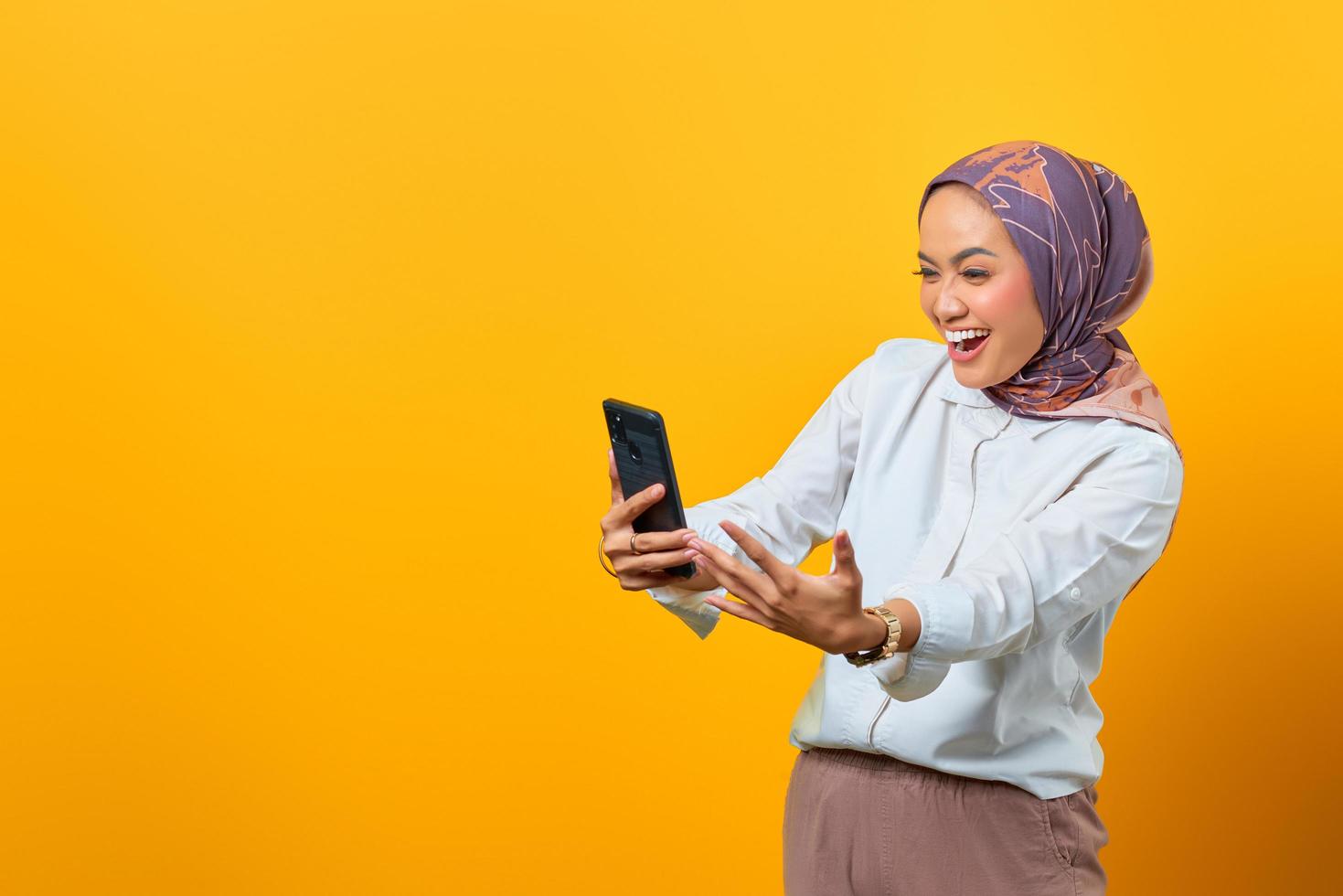 Aufgeregte asiatische Frau, die auf Smartphone schaut und gute Nachrichten erhält foto