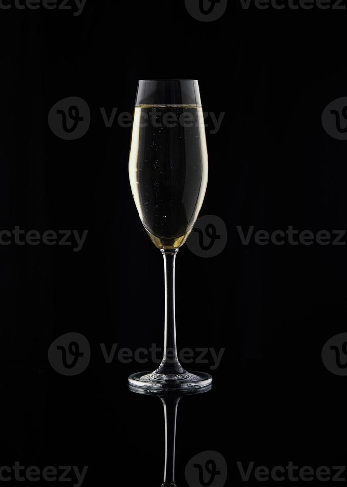 Glas mit Champagner auf schwarzem Hintergrund mit Umriss e Seiten foto