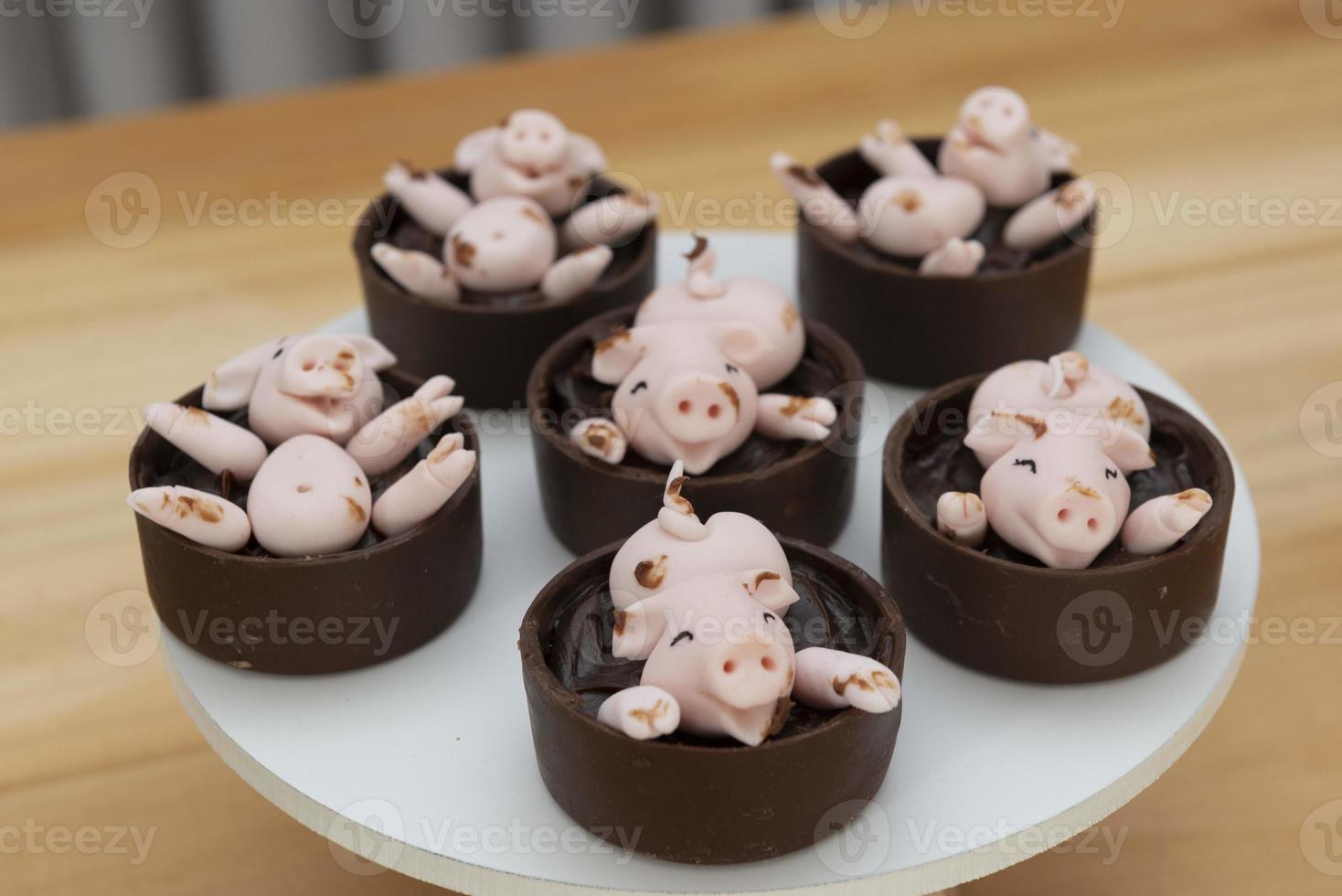 dekorierte Bonbons, glückliche süße rosa Schweine, die im Schlamm spielen foto