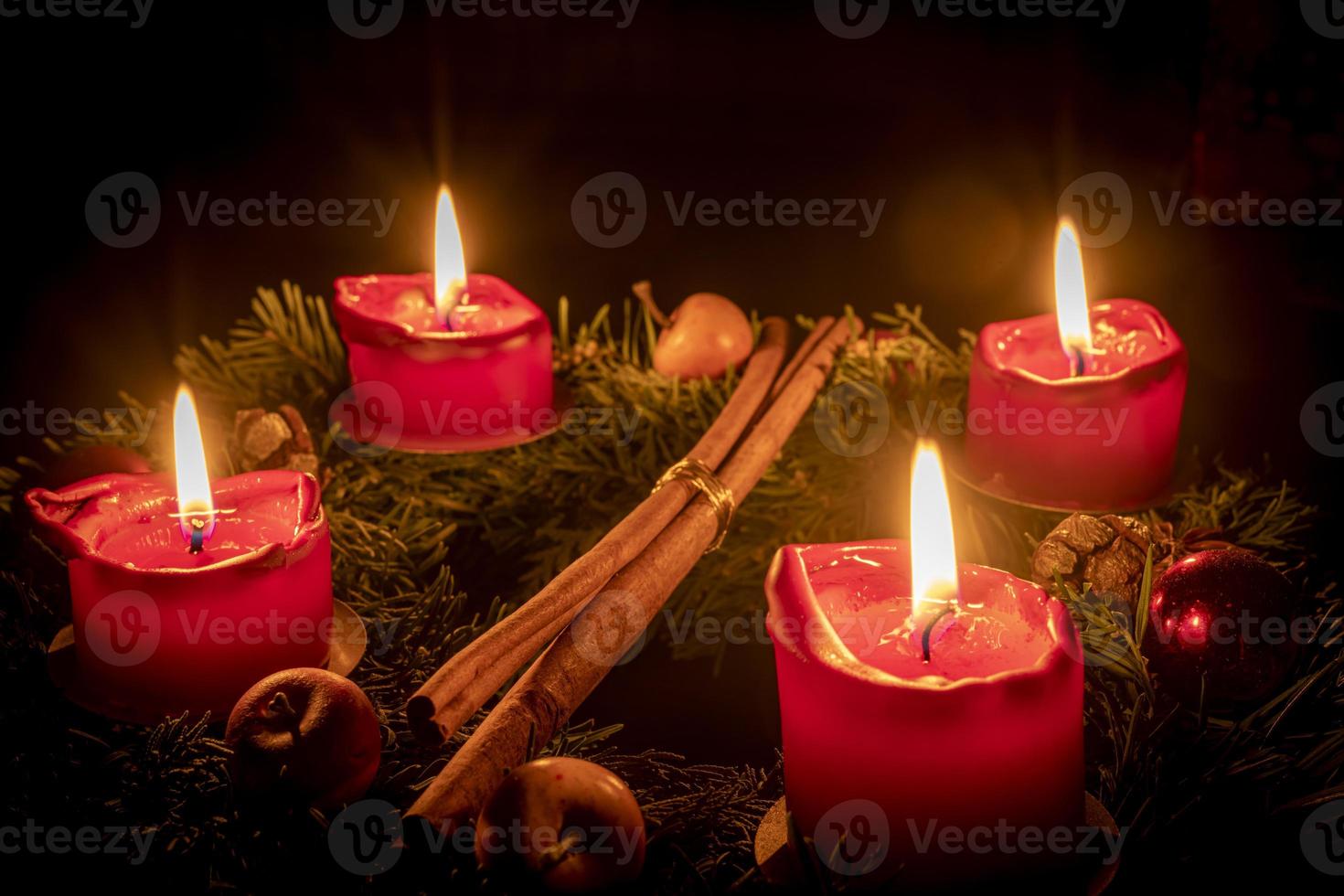 geschmückter Adventskranz aus Tannenzweigen mit brennenden roten Kerzen foto