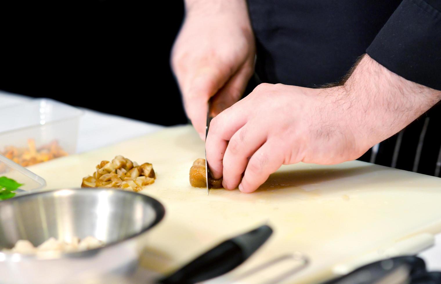 Küchenchef schneidet das Gemüse, das in einer Küche kocht, Gemüse zubereiten foto