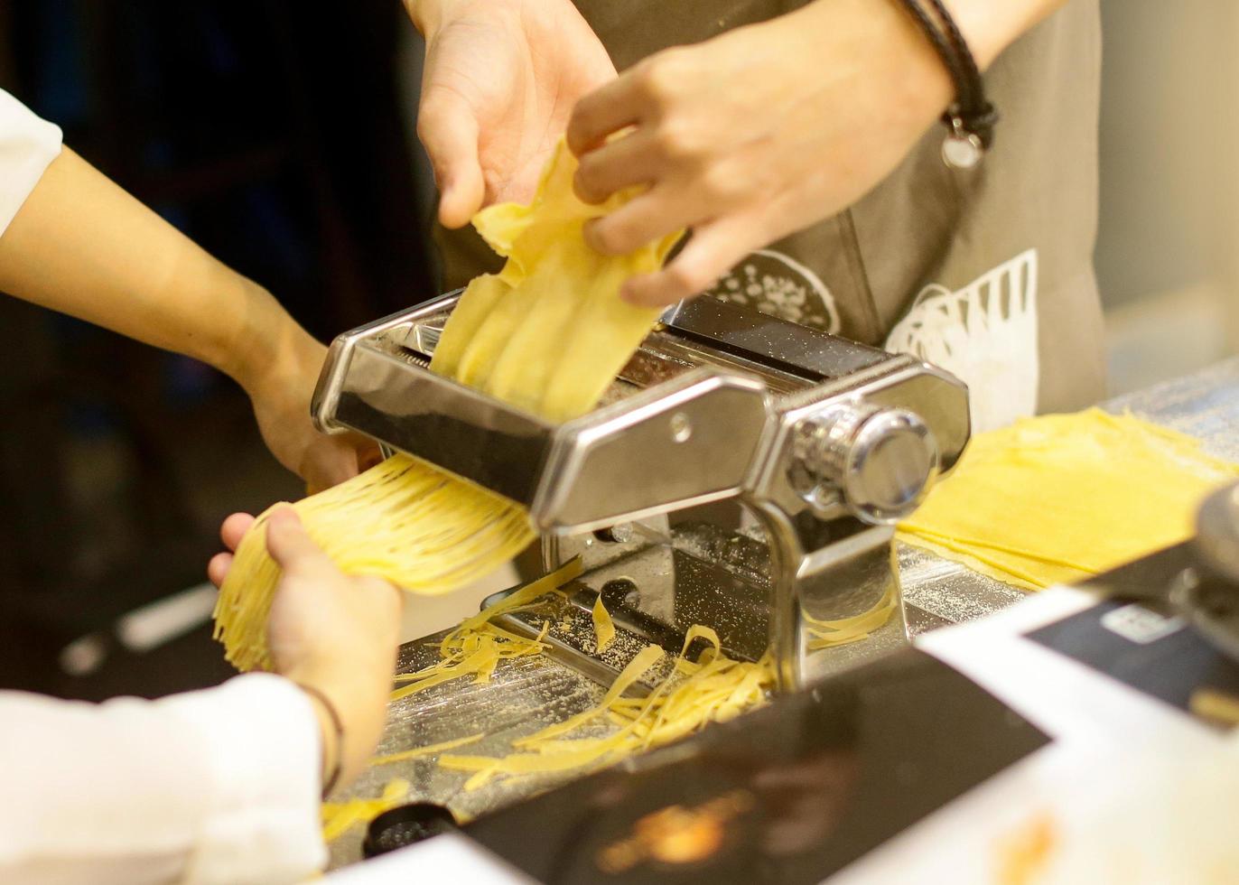 Koch macht Pasta mit einer Maschine, hausgemachte frische Pasta foto