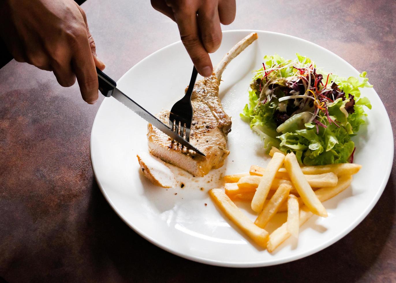 Schweinekotelettsteak mit Salat und Pommes frites foto