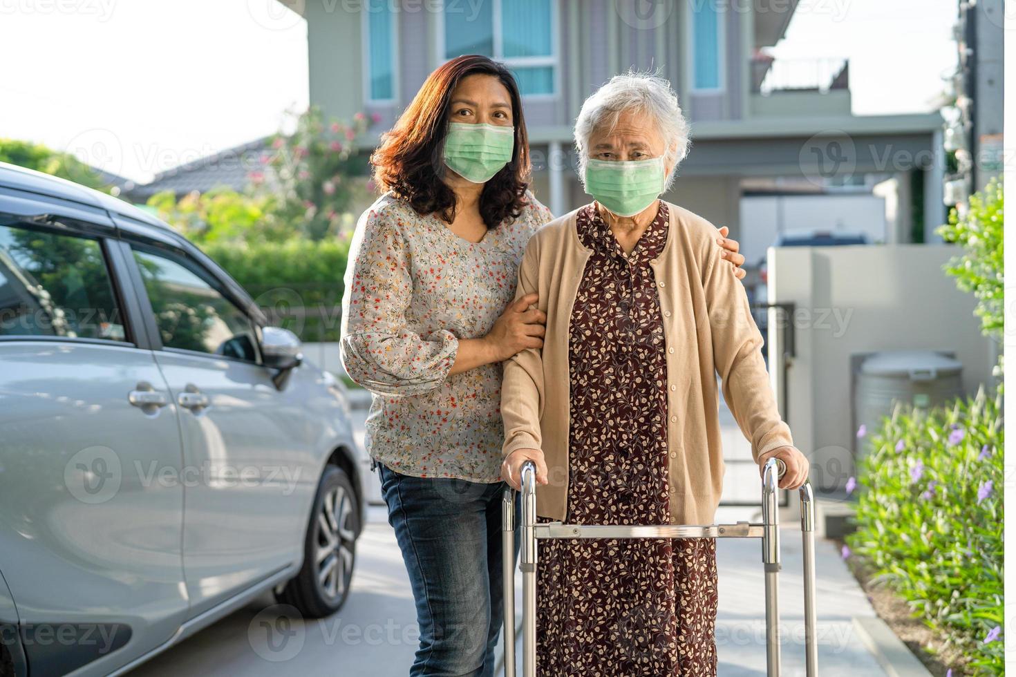 Asiatische Seniorin geht mit einem Wanderer, der eine Maske trägt, um das Coronavirus zu schützen. foto