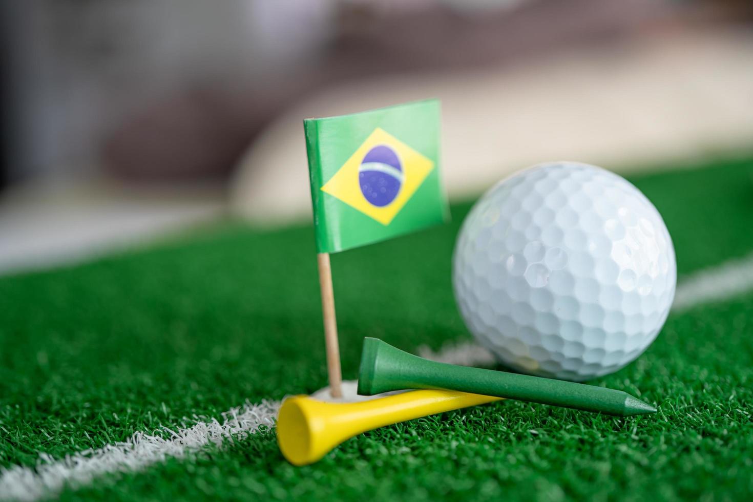 Golfball mit Brasilien-Flagge und Tee auf grünem Rasen foto