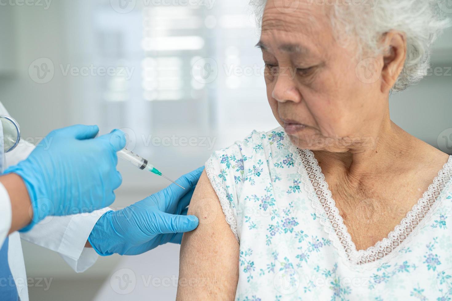 Ältere asiatische Seniorin, die gegen Covid-19 oder Coronavirus-Impfstoff erhält foto