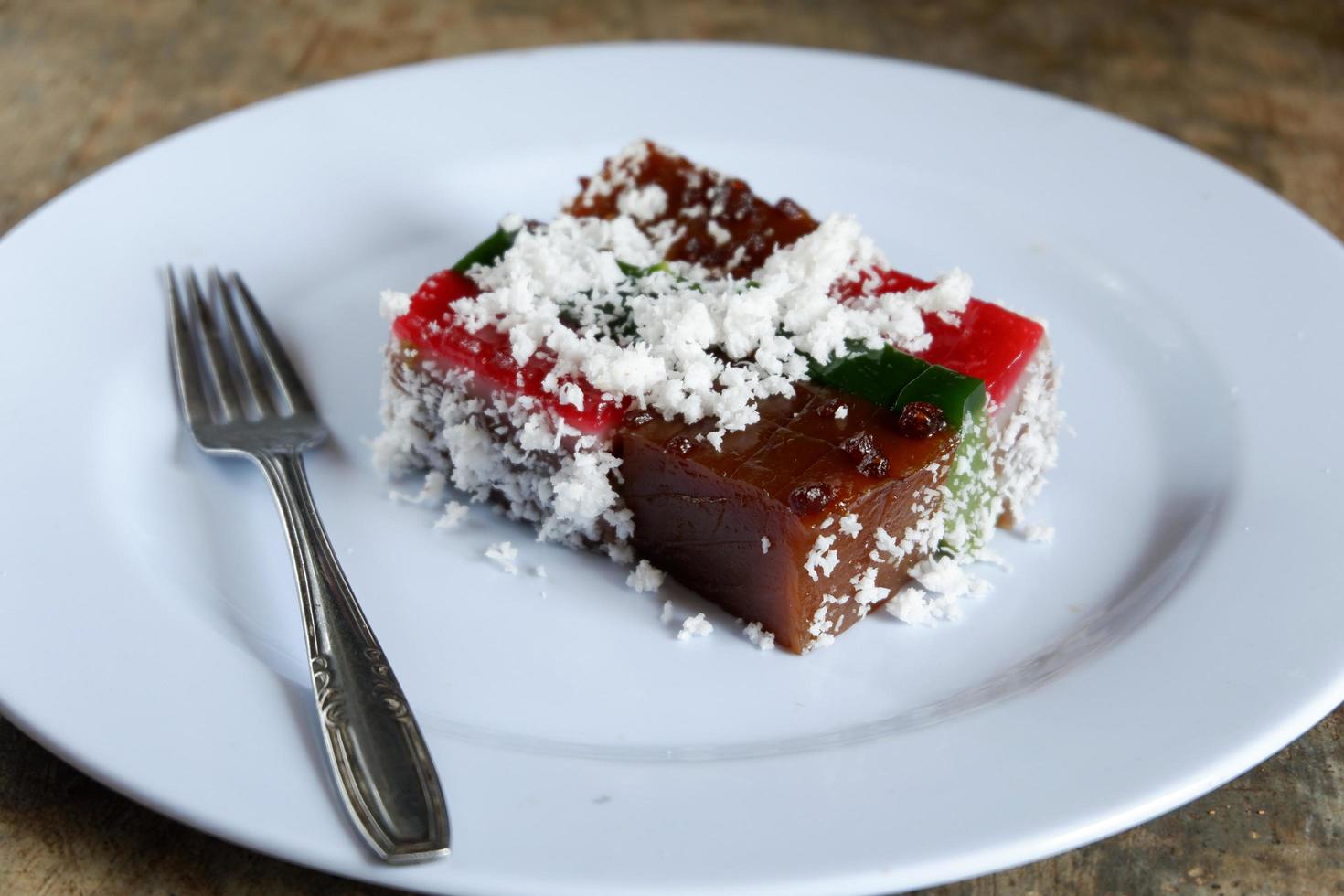 Schichtkuchen und Kokosraspeln auf Teller mit Besteck, malaiisches Essen foto