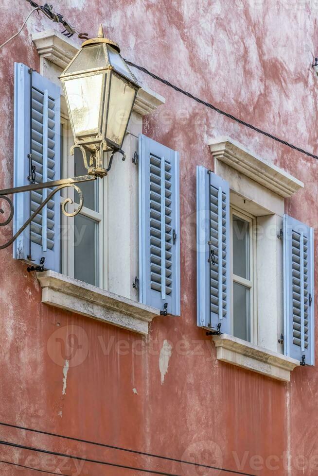 Bild von ein Fassade von ein Antiquität Haus mit Fenster mit Blau Fensterläden und ein historisch Straße Lampe foto