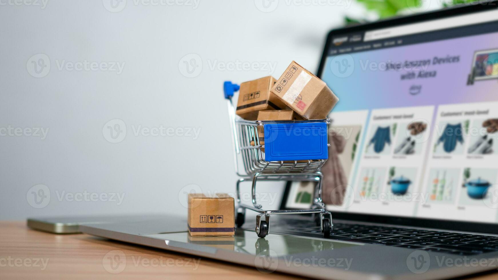 Einkaufen Wagen und Produkt Kisten platziert auf Laptop Computer vertreten online Einkaufen Konzept, Webseite, E-Commerce, Marktplatz Plattform, Technologie und online Zahlung Konzept. foto