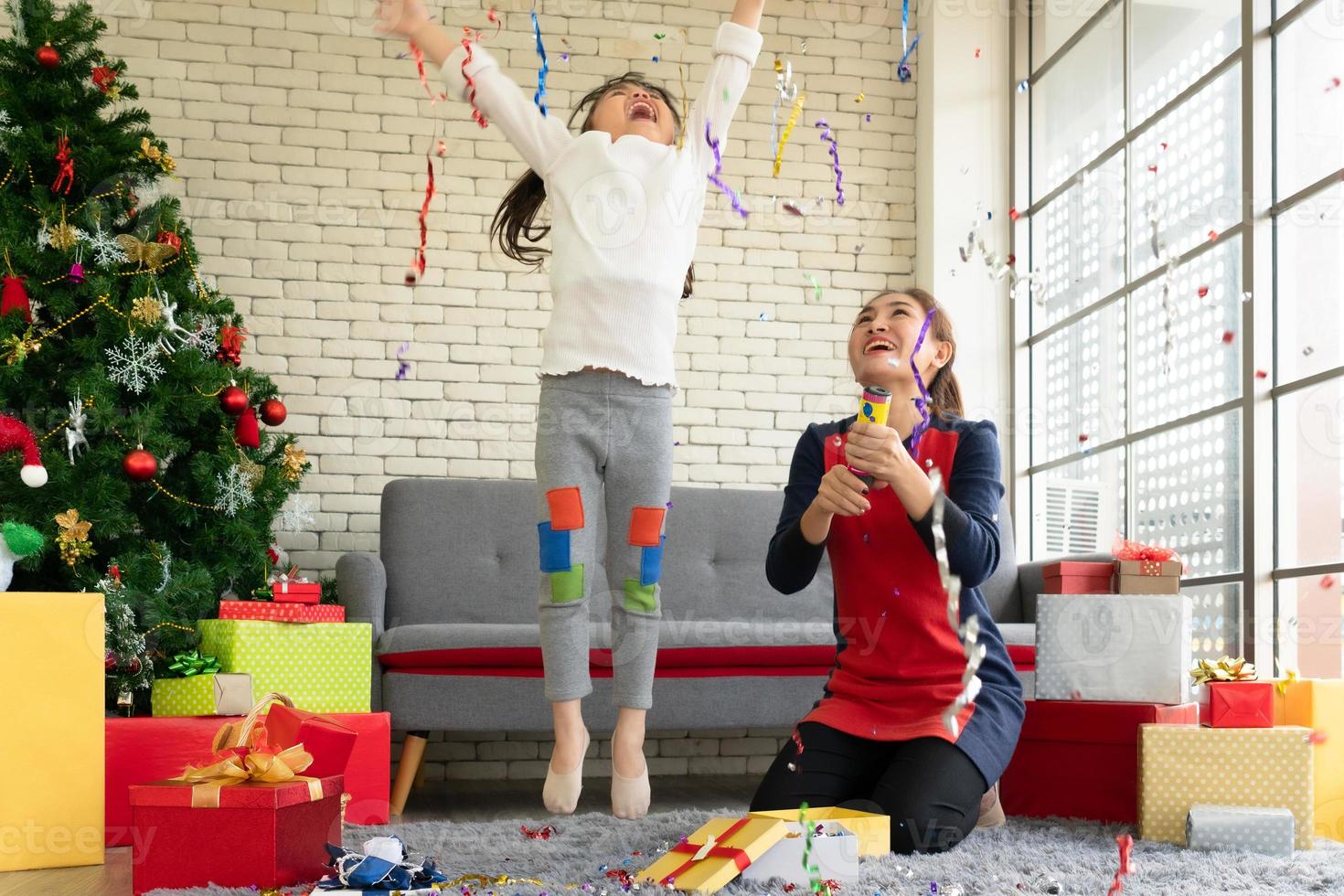asiatische mutter und kind feiern weihnachten mit konfetti zu hause foto