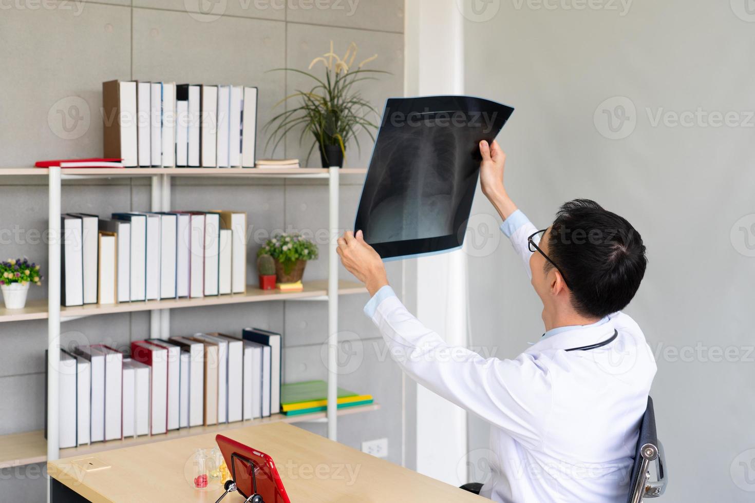 junger Arzt, der Cxr des Patienten im Bürokrankenhaus betrachtet foto