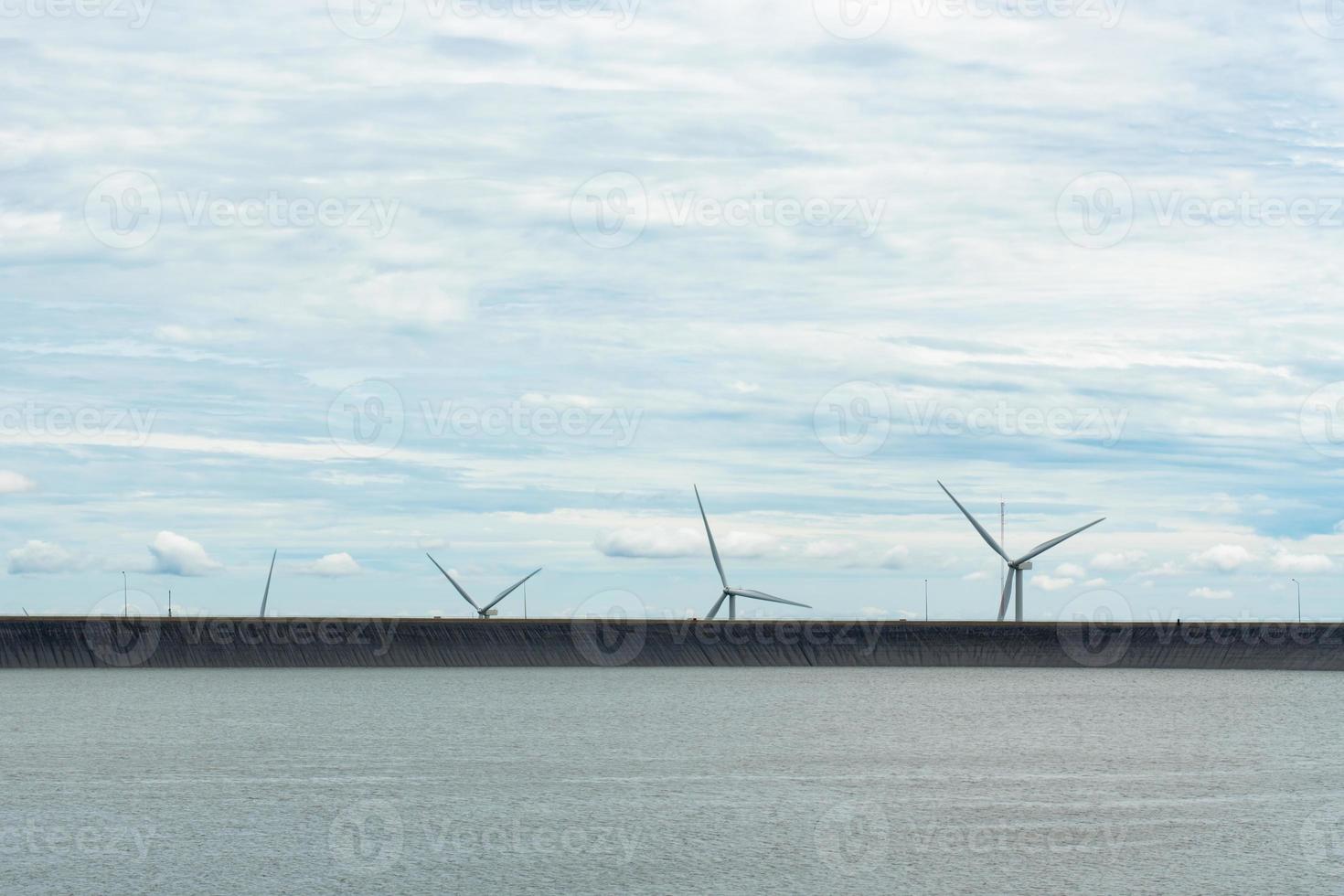 Windkraftanlage zur Erzeugung von erneuerbarem Strom und der Damm foto