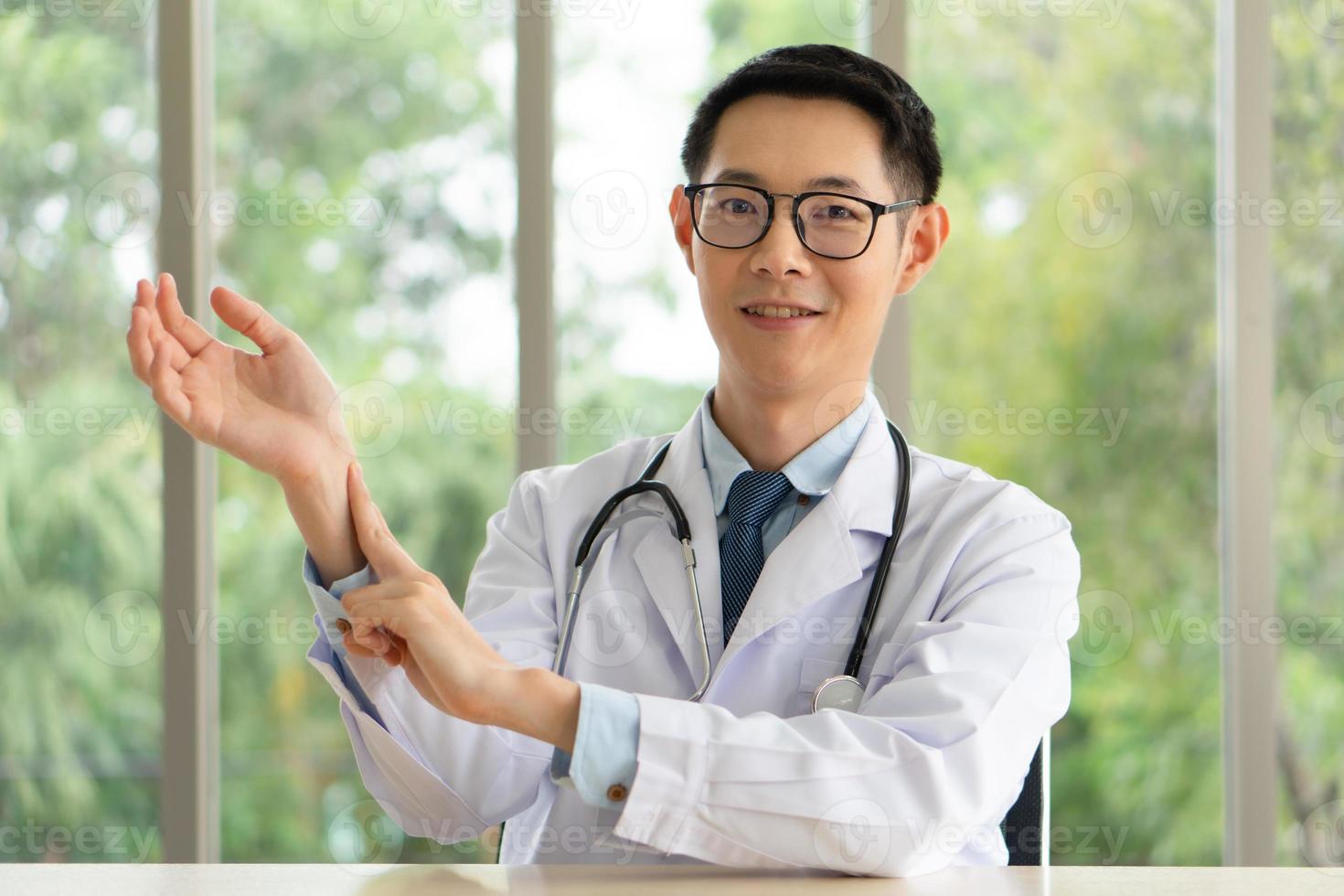 Asiatischer Arzt, der zeigt, wie man den radialen Puls per Videoanruf-App palpiert foto