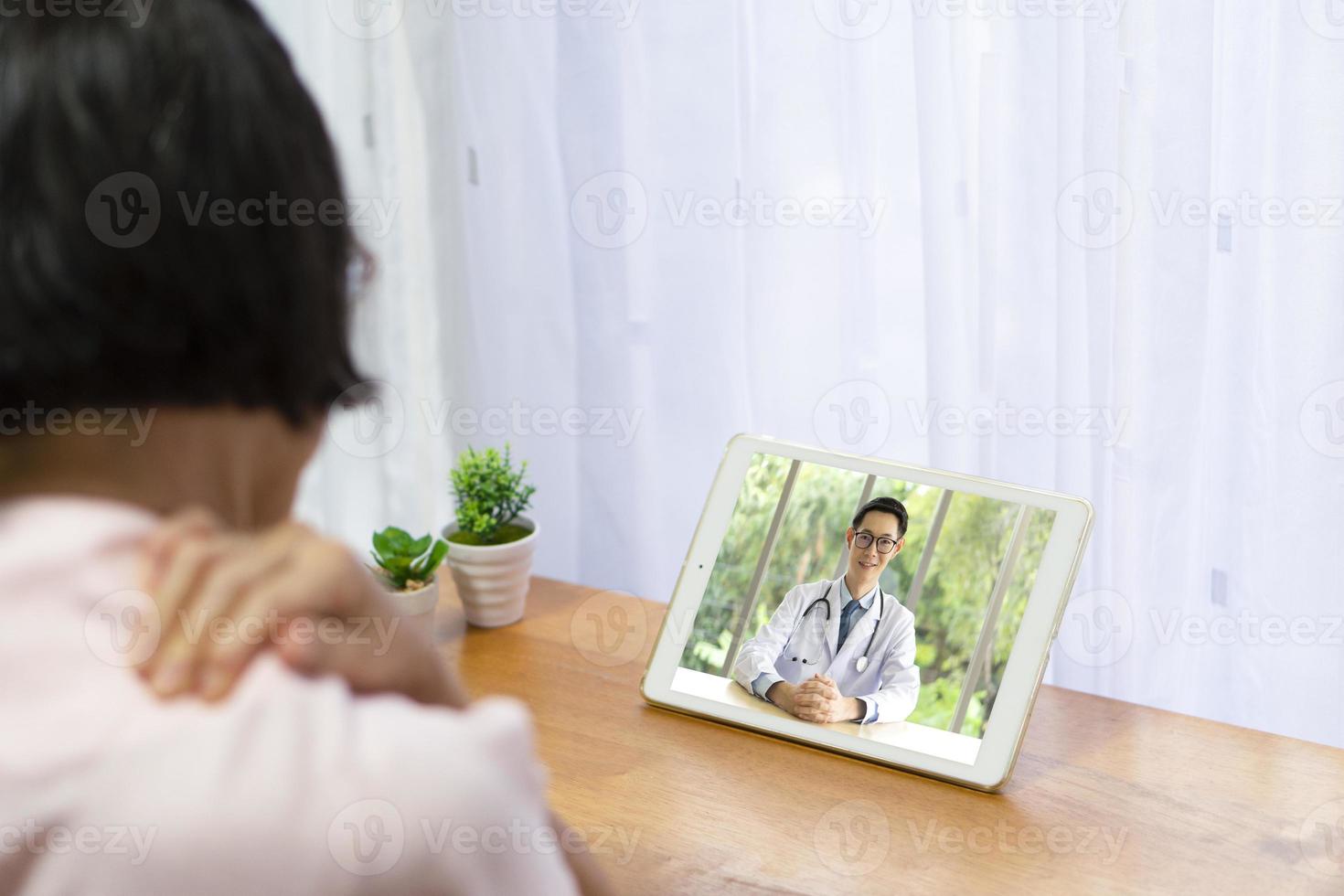 älterer Patient konsultieren online einen Arzt über Schulterschmerzen foto