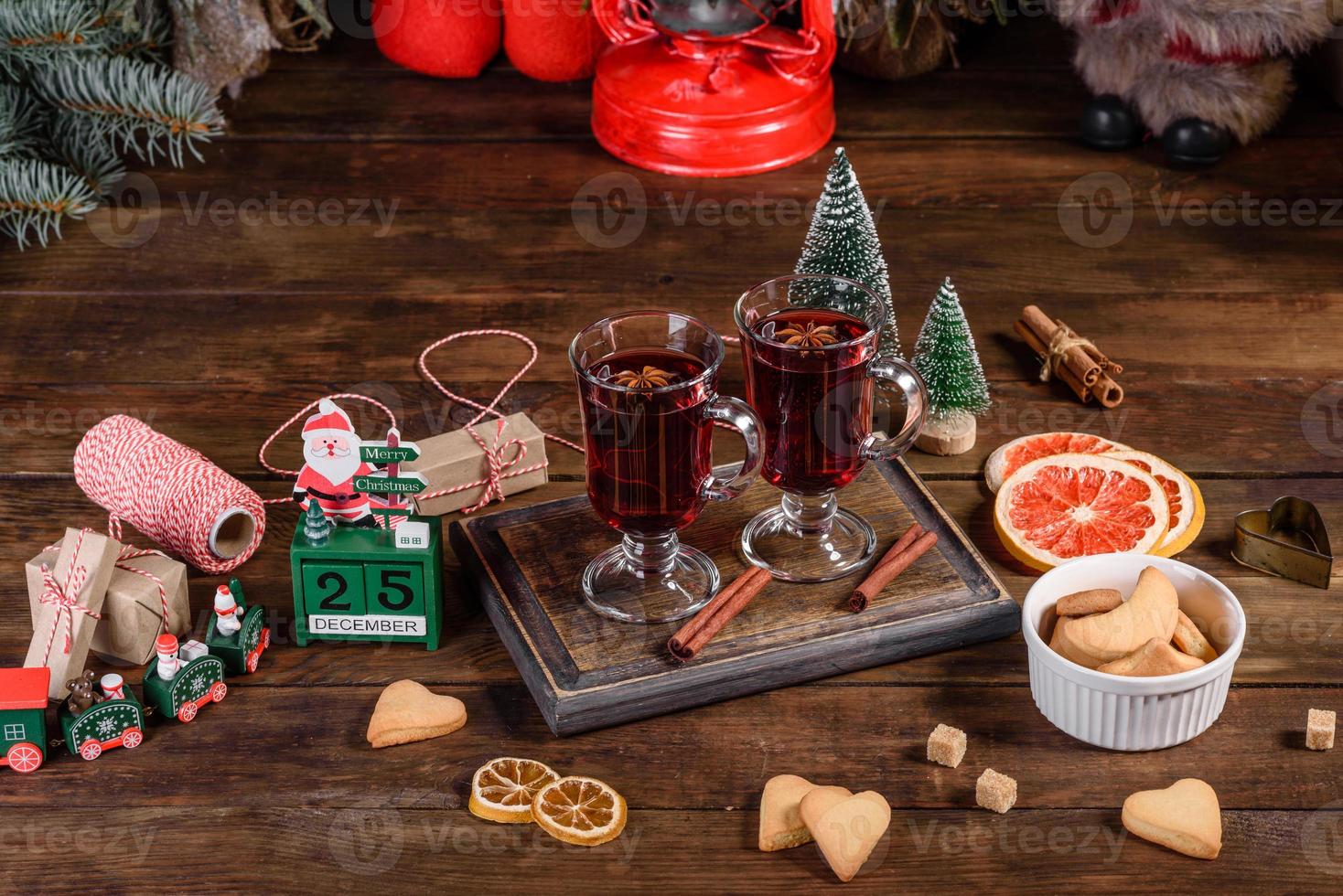 Weihnachtsglühwein mit Gewürzen und Früchten auf einem dunklen Tisch. foto