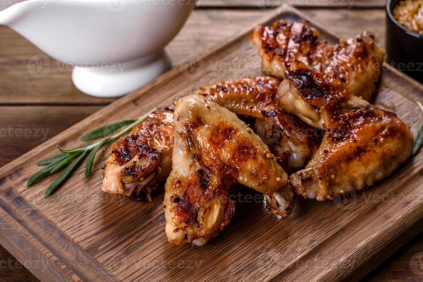 gegrillte würzige Hähnchenflügel auf dunklem Hintergrund mit Gewürzen und Kräutern foto