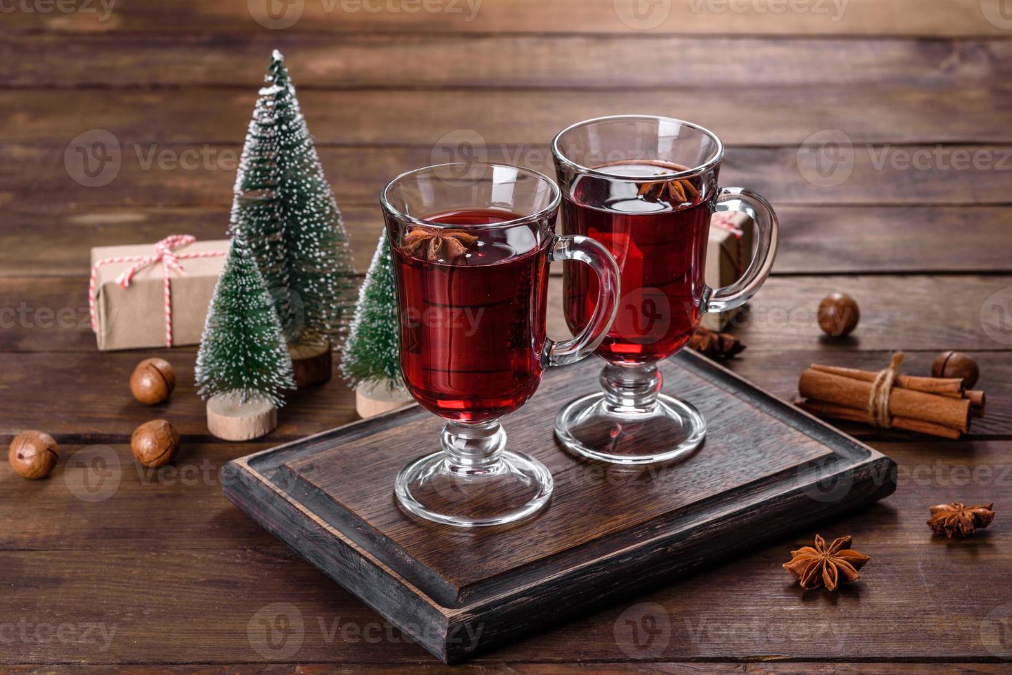 Weihnachtsglühwein mit Gewürzen und Früchten auf einem dunklen Tisch. foto