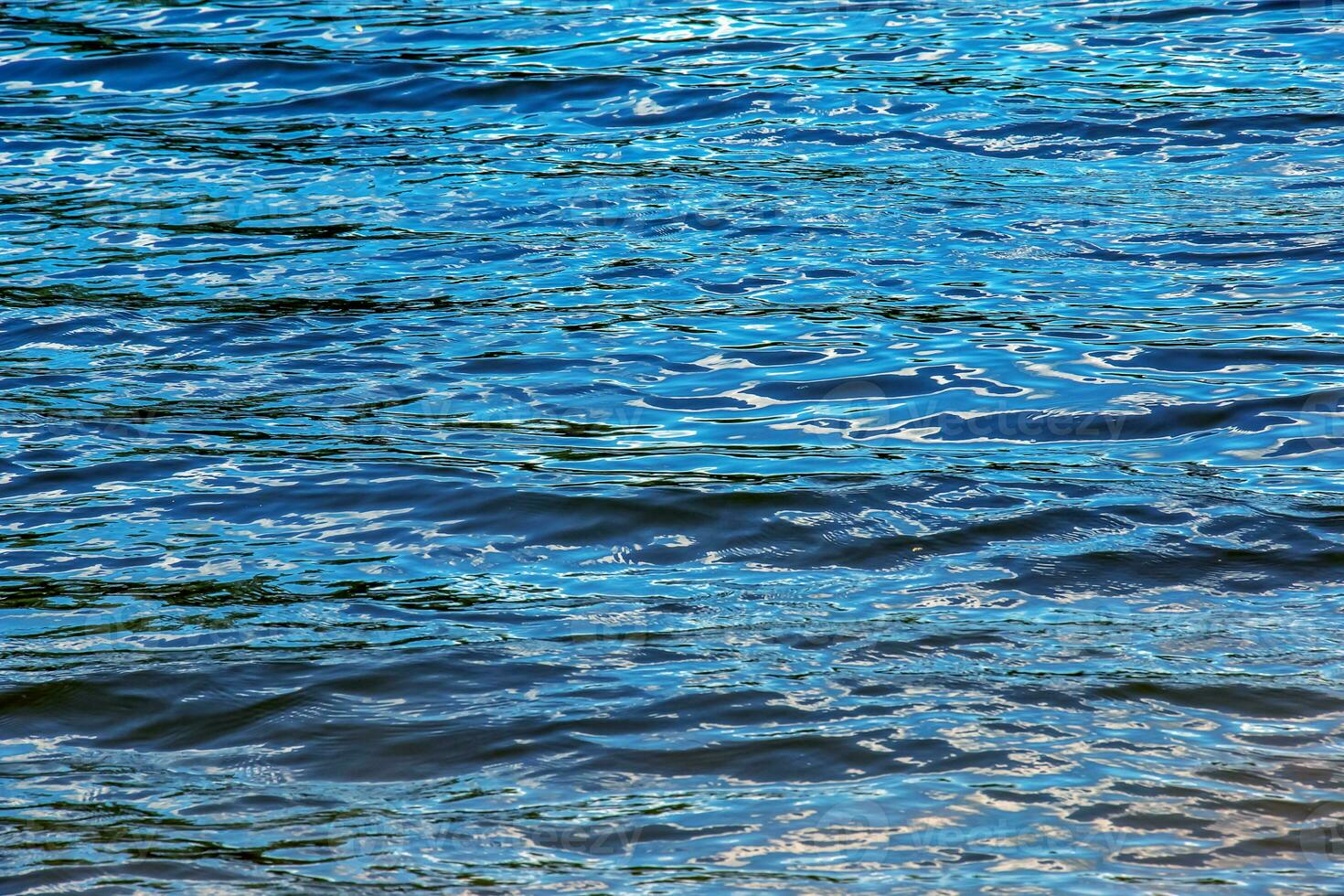 Wasserkräuselung Textur Hintergrund. Wellenförmige Wasseroberfläche bei Sonnenuntergang, goldenes Licht, das sich im Wasser spiegelt. foto