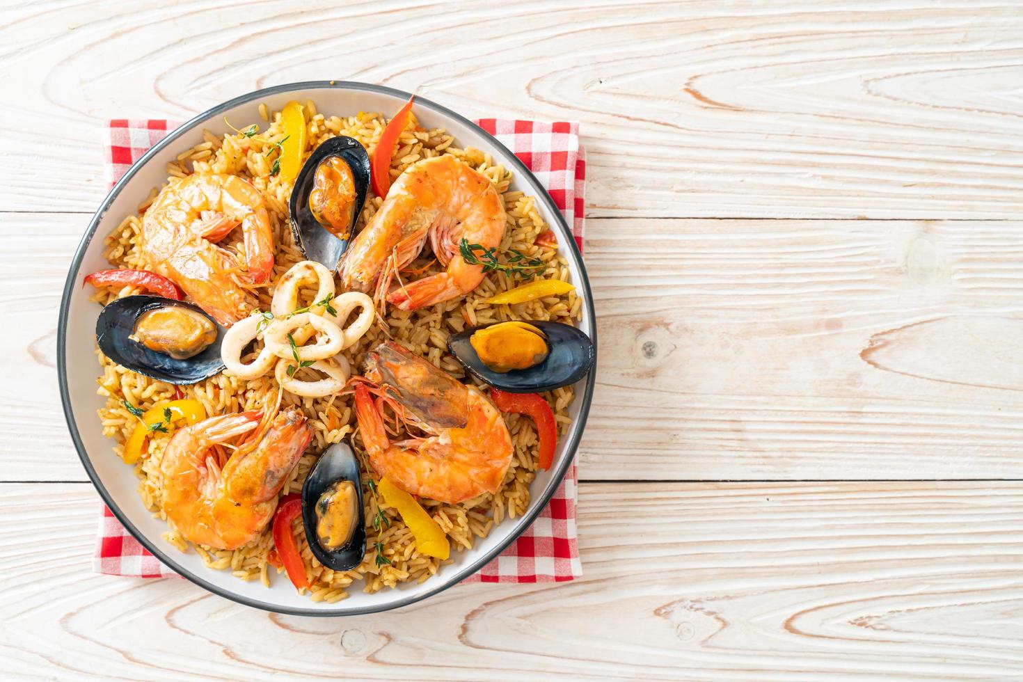 Meeresfrüchte-Paella mit Garnelen, Venusmuscheln, Miesmuscheln auf Safranreis foto