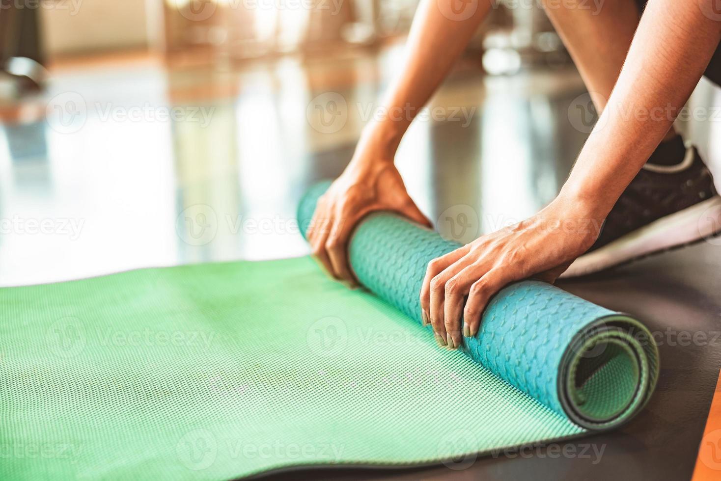 Nahaufnahme einer sportlichen Frau, die Yoga-Matratze im Sport-Fitnessstudio faltet? foto