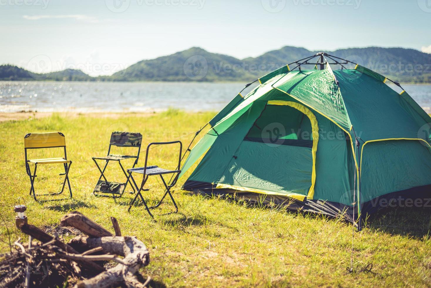 Campingzelt mit gelöschtem Lagerfeuer auf der grünen Wiese foto