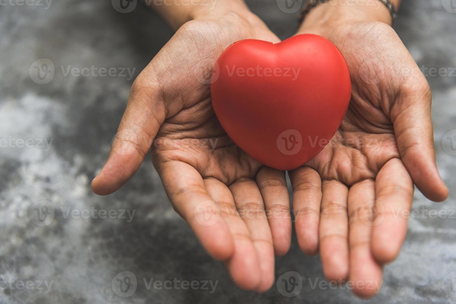 Nahaufnahme von weiblichen Händen, die rotes Herz als Herzspender geben foto