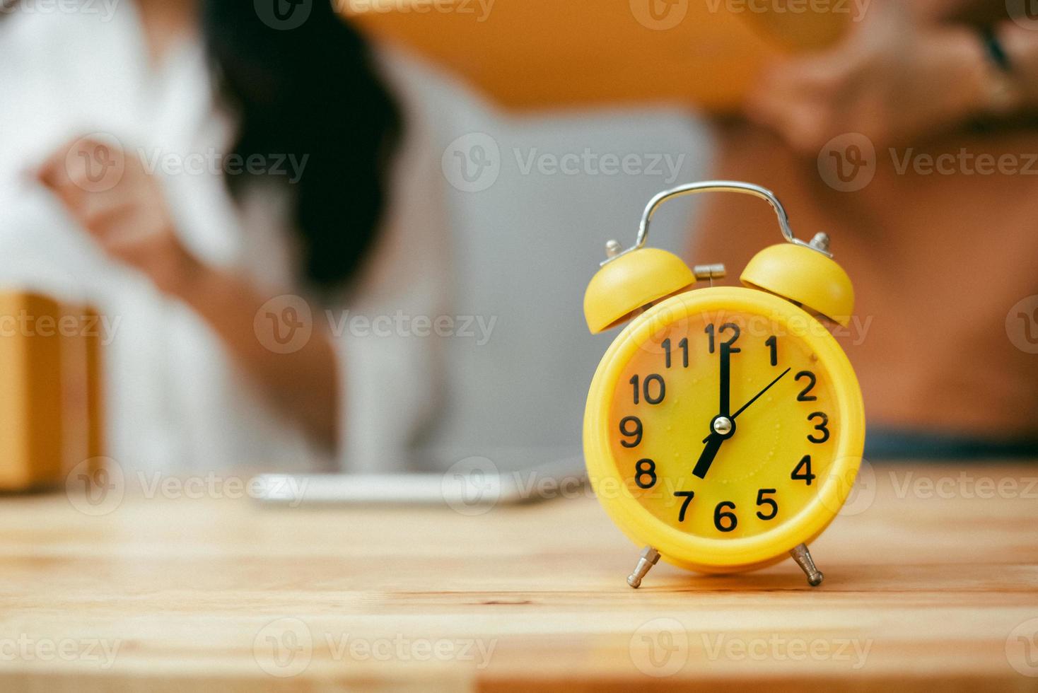 gelber Wecker auf Holztisch im Büro foto