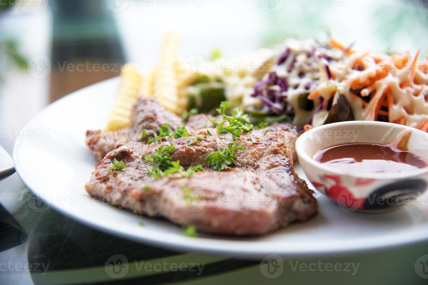 Schweinekotelettsteak mit Salat und Soße in einer Schale foto