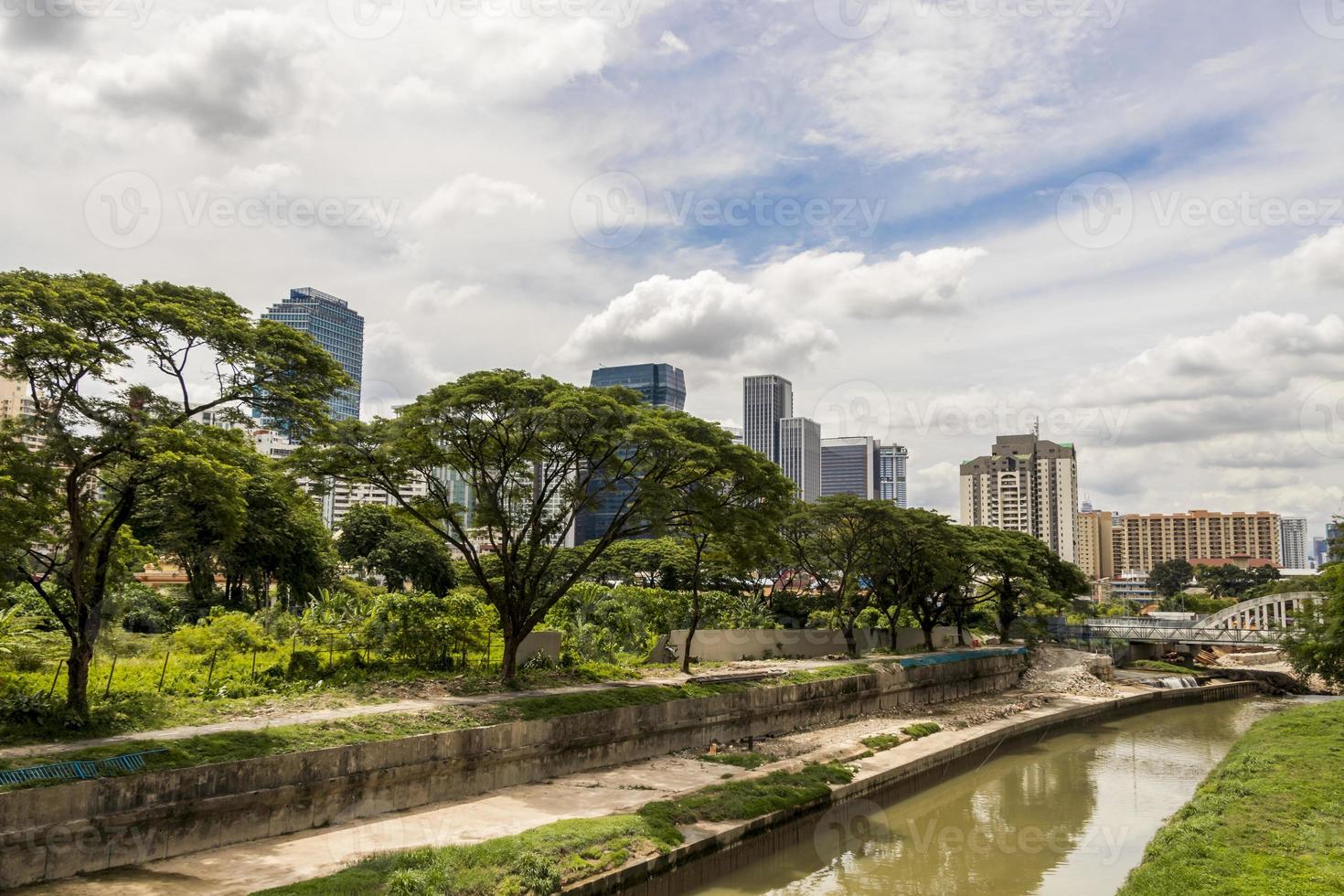 riesige wolkenkratzer hinter tropischer natur und fluss, kuala lumpur. foto