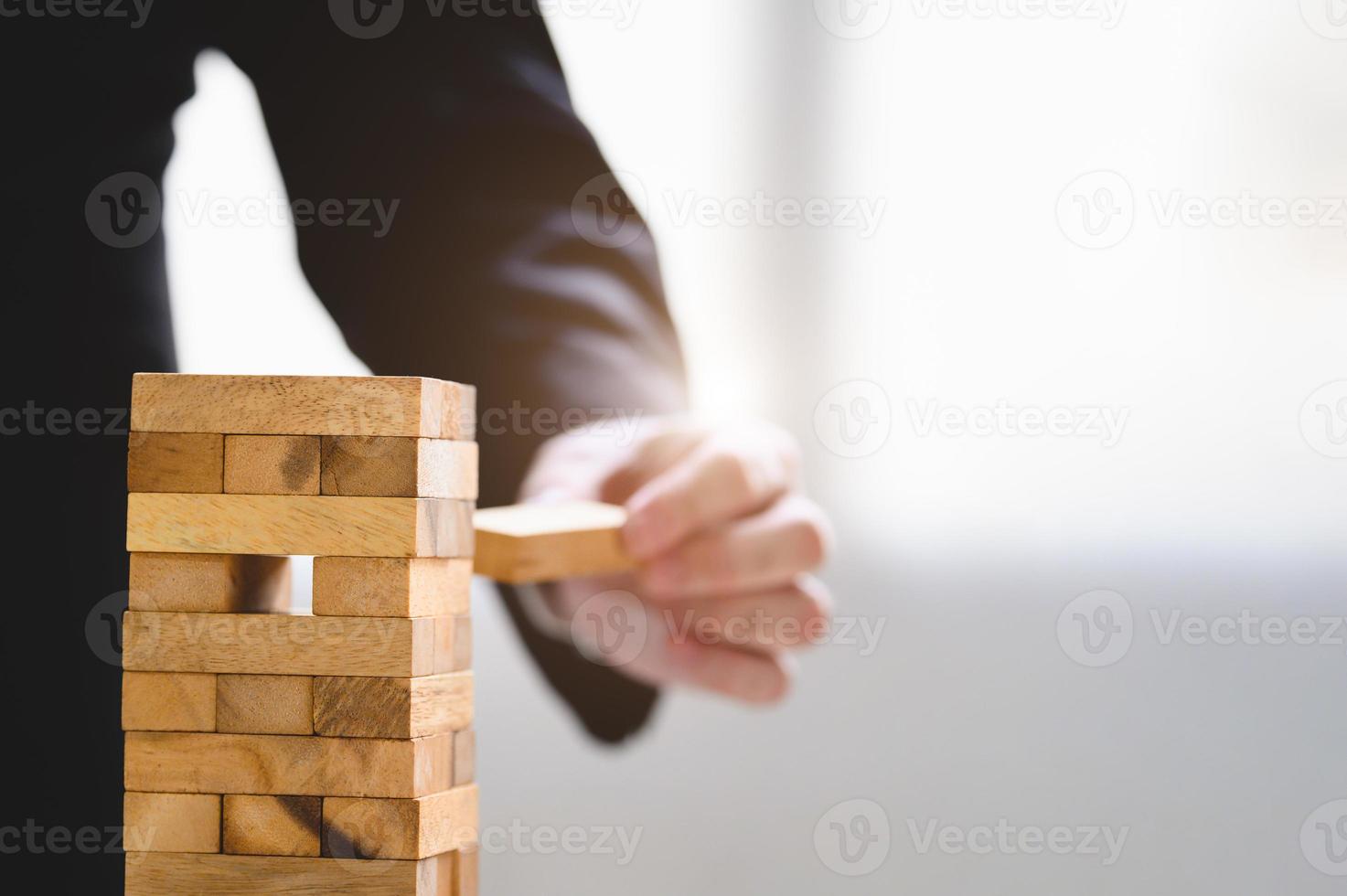 Geschäftsmann nimmt und pflücke einen Holzblock auf gestapeltem Turm foto