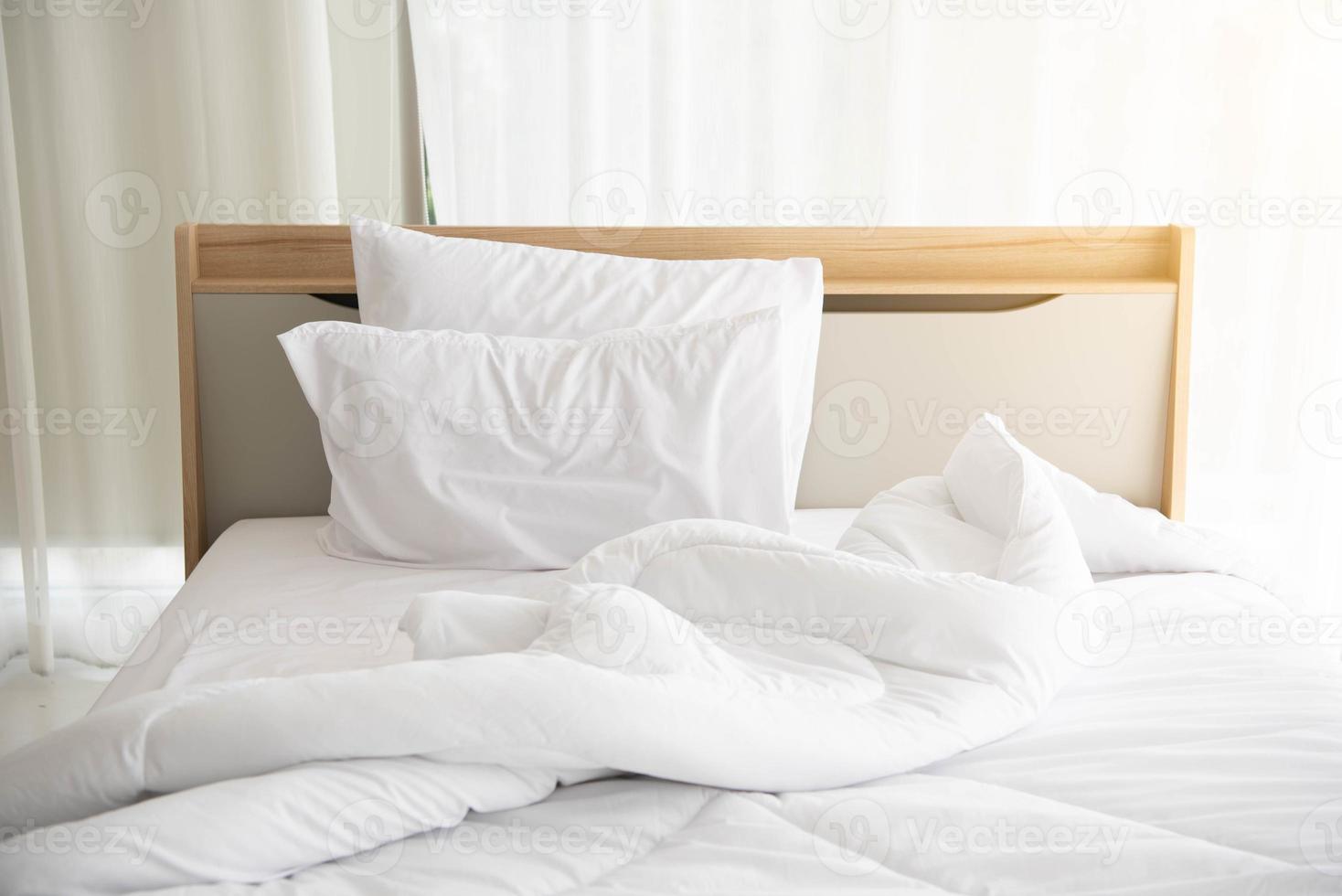 weißes ungemachtes Bett am Morgen mit Sonnenschein mit weißem Vorhang foto