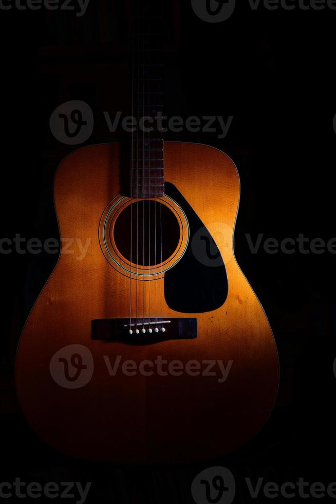 Akustikgitarre auf schwarzem Hintergrund zwischen Licht oder Schatten foto