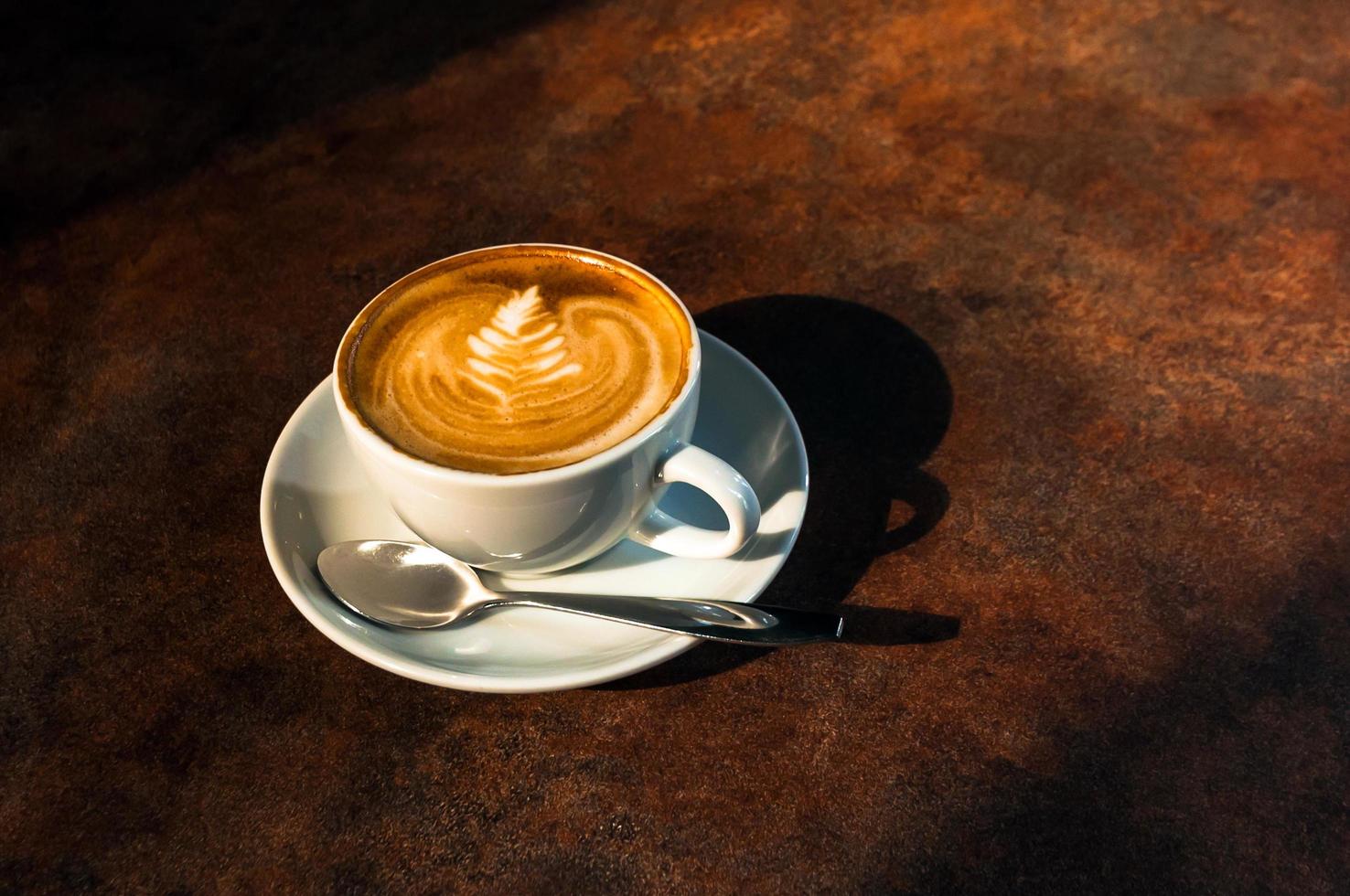 Tasse heiße Latte Art im Nachmittagslicht auf Tischrestaurant foto